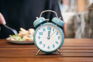 Benefits of Intermittent Fasting, clock on the table showing time.